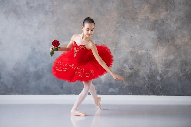 Foto uma menina bonitinha sonha em se tornar uma bailarina profissional uma garota em um tutu vermelho brilhante em sapatilhas dança no corredor estudante de escola profissional