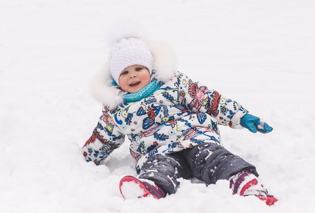 Uma menina brinca com a neve no inverno