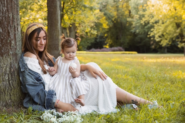 Uma menina caminha com a mãe ao ar livre.