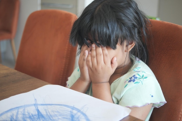 Uma menina chateada cobre o rosto com a mão