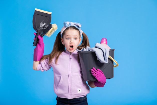 Uma menina chocada vê a quantidade de limpeza que espera por seu filho surpreso segurando balde com esfregão