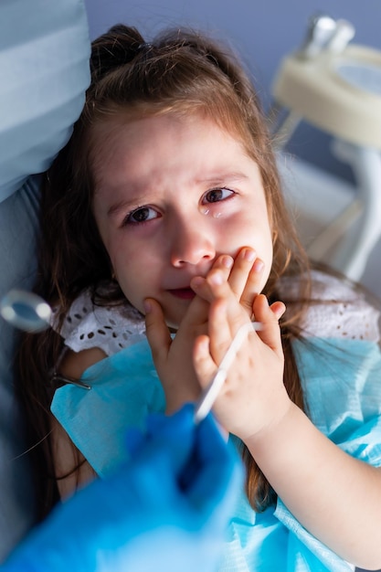 Uma menina chorando em uma cadeira de dentista