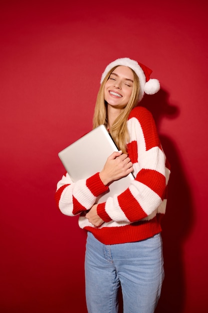 Uma menina com chapéu asanta segurando um laptop