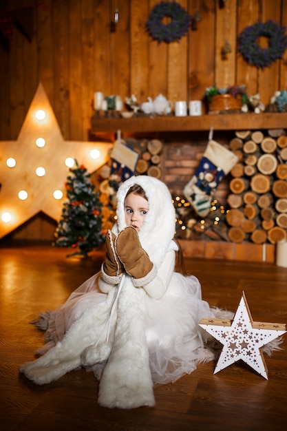 Uma menina com roupas quentes encontra a noite de Natal em uma cabana de madeira