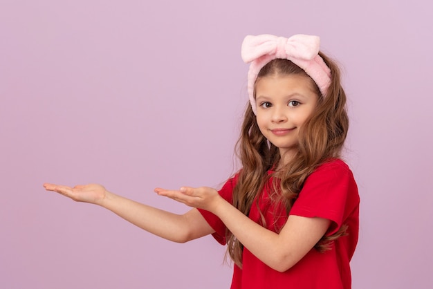 Uma menina com um arco na cabeça aponta para o anúncio com as mãos