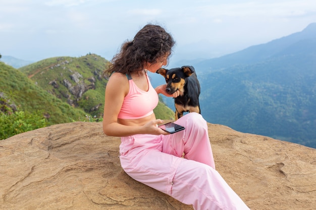 Uma menina com um cachorro, apreciando a paisagem montanhosa à beira de um precipício