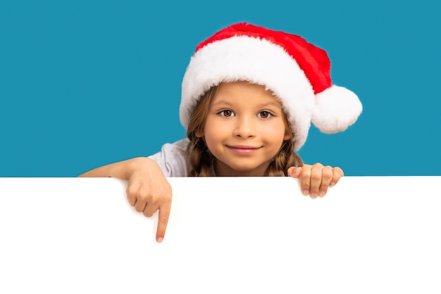 Uma menina com um chapéu de Natal aponta para o seu anúncio