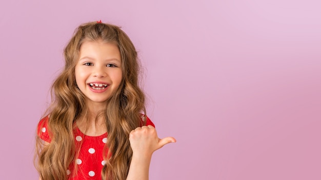 Uma menina com um fundo roxo sorri e aponta o polegar para o lado.