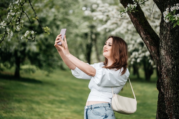 Uma menina com um telefone na mão tira fotos de selfies, fotos para a Internet