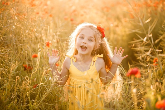 Uma menina com um vestido amarelo corre em flores de papoula vermelhas em um fundo de grama verde