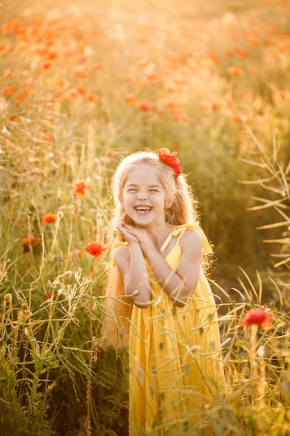 Uma menina com um vestido amarelo corre em flores vermelhas de papoula em um fundo de grama verde