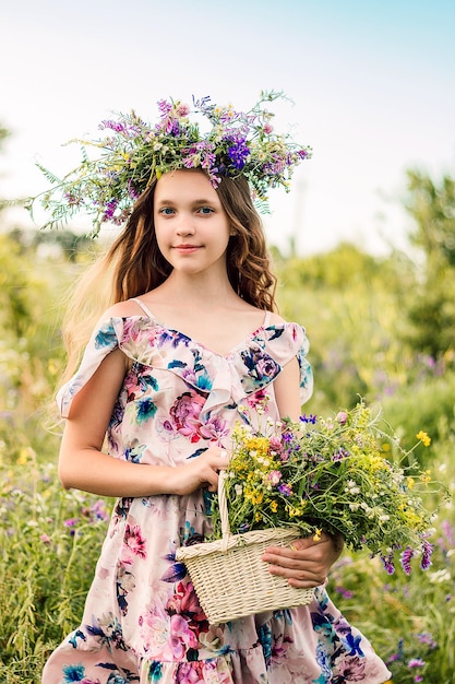 Uma menina com uma coroa de flores silvestres na cabeça está em um campo