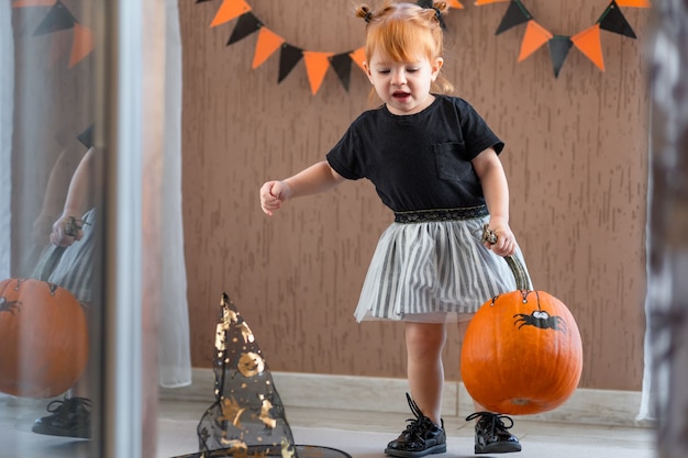 Foto uma menina com uma fantasia de bruxa pinta abóboras para o halloween em casa o conceito de criação infantil.