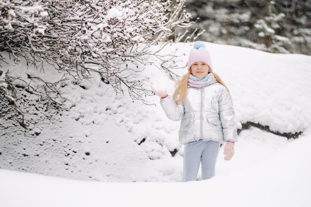 Uma menina com uma jaqueta prateada no inverno sai no inverno