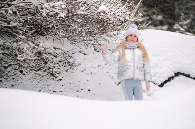 Uma menina com uma jaqueta prateada no inverno sai no inverno