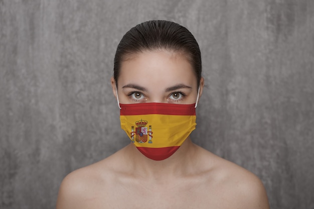 Foto uma menina com uma máscara no rosto com a bandeira do país da espanha