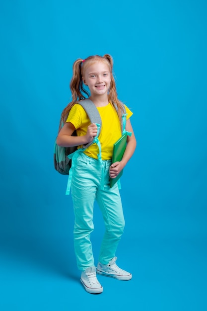 Uma menina com uma mochila segurando um livro sobre um fundo azul