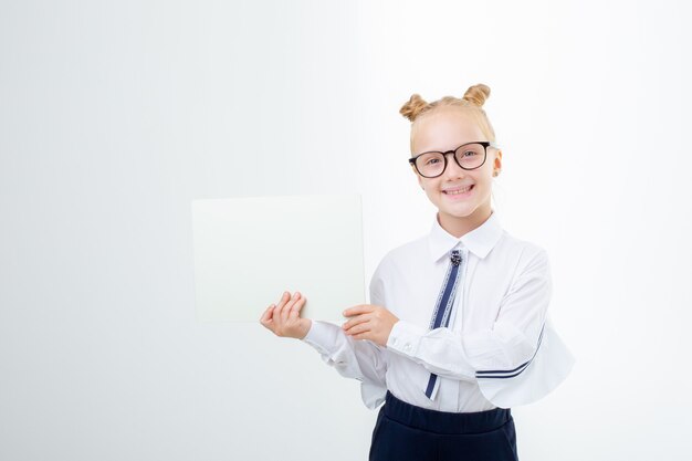 Uma menina com uniforme escolar segura uma folha de papel vazia nas mãos