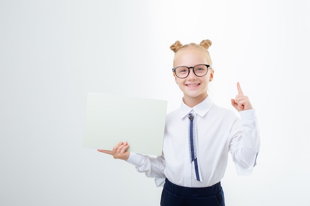 Uma menina com uniforme escolar segura uma folha de papel vazia nas mãos