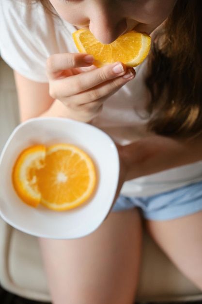 Uma menina come uma fatia de laranja de perto sem olhos vitamina nutrição frutas