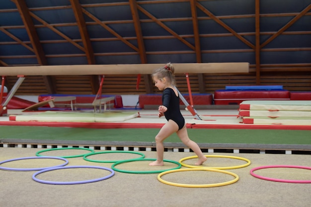 Uma menina corre através de hula hoops no ginásio