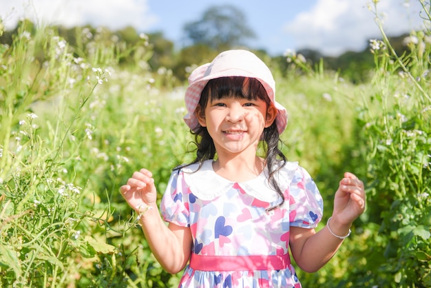 Uma menina criança asiática se diverte com um rosto feliz e sorridente, crianças brincando do lado de fora da flor do jardim