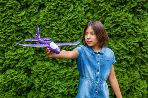 Uma menina criança tem um avião de brinquedo nas mãos