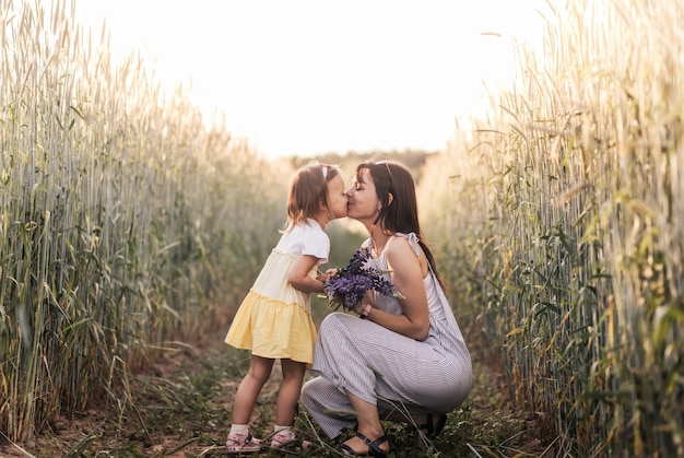 Foto uma menina dá um buquê de tremoços para a mãe no campo no verão. conceito de amor e família feliz