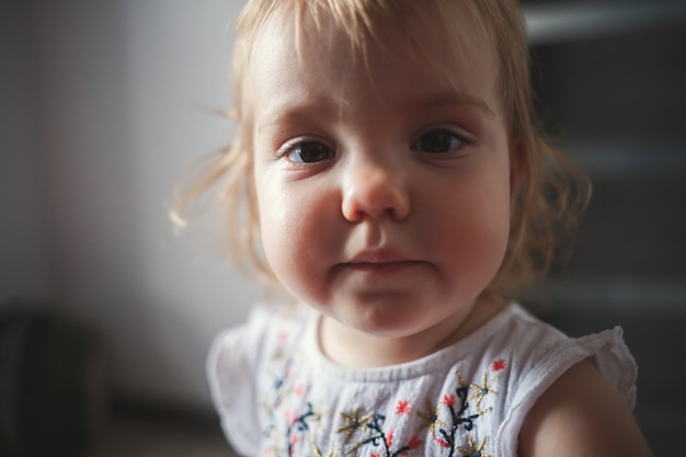 Uma menina de 1,5 anos está de pé e sorrindo. A criança dança e caminha. Menina alegre no apartamento