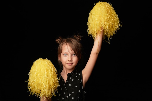 Uma menina de 6 anos em um fundo preto Uma líder de torcida com bombas amarelasDesporto e energia