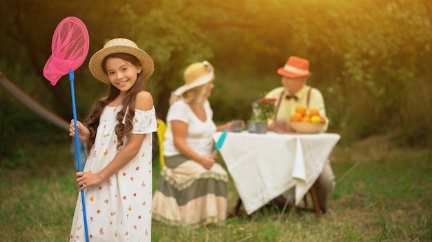 Uma menina de cabelo escuro bonito em sundress com uma rede cor-de-rosa da borboleta.