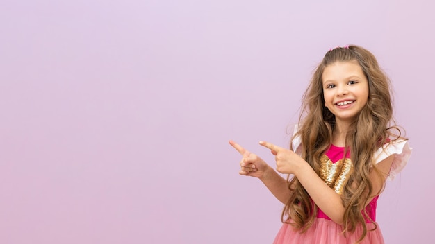 Uma menina de cabelos cacheados e um lindo vestido rosa aponta o dedo para o seu anúncio.