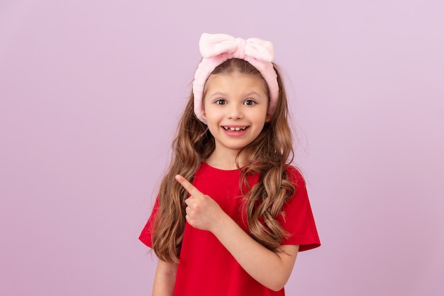 Uma menina de camiseta vermelha aponta o dedo para o anúncio.