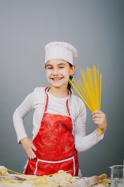 Uma menina de chapéu de cozinheiro está preparando o jantar