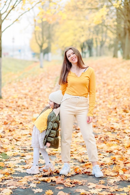 Uma menina de cinco anos, abrindo a boca com admiração e alegria, brinca com a mãe no parque de outono. mãe e filha se divertem ao ar livre no outono