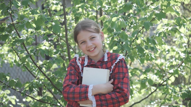 Uma menina de nove anos, uma estudante do ensino fundamental em um uniforme escolar com um livro nas mãos