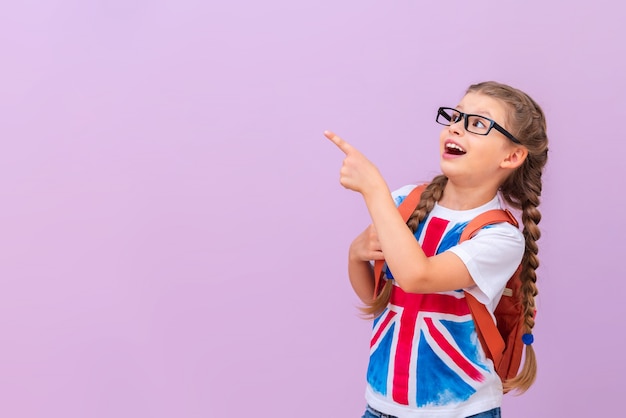 Uma menina de óculos com uma mochila e uma camisa com uma bandeira britânica aponta para o seu anúncio.