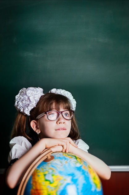 Uma menina de óculos na recepção na sala de aula está sonhando.