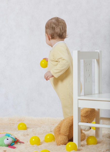 Uma menina de oito meses vestida com um pijama amarelo brinca em seu quarto