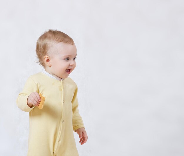 Uma menina de oito meses vestida com um pijama amarelo brinca em seu quarto