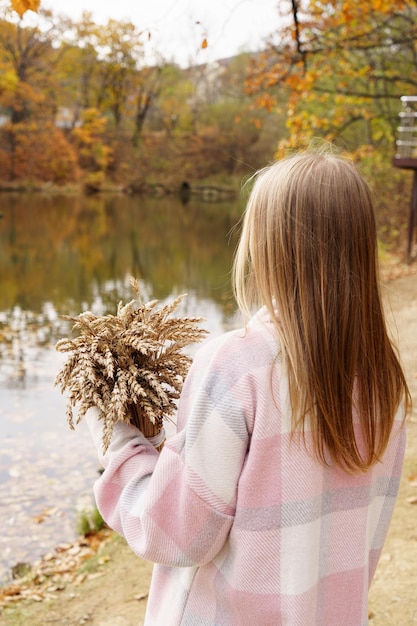 Uma menina de pé perto de um lago de outono