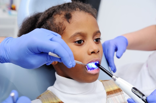 Uma menina de pele escura na cadeira do dentista