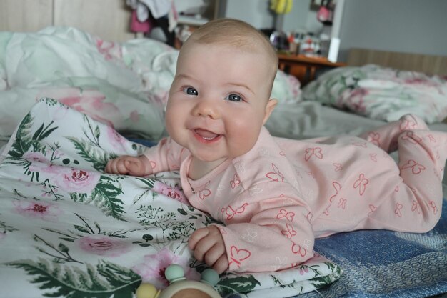 Foto uma menina de quatro meses de idade deita-se num lençol branco com uma inscrição e bordados abertos