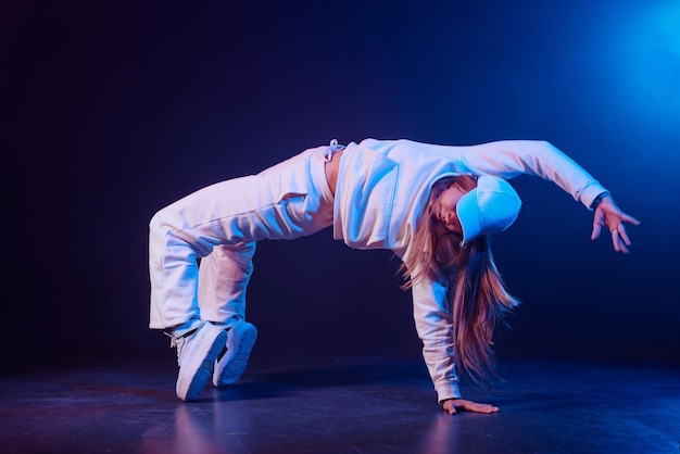 uma menina de roupas leves dança em um fundo de néon em fumaça dança moderna