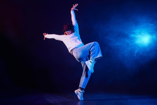 uma menina de roupas leves dança em um fundo de néon em fumaça dança moderna