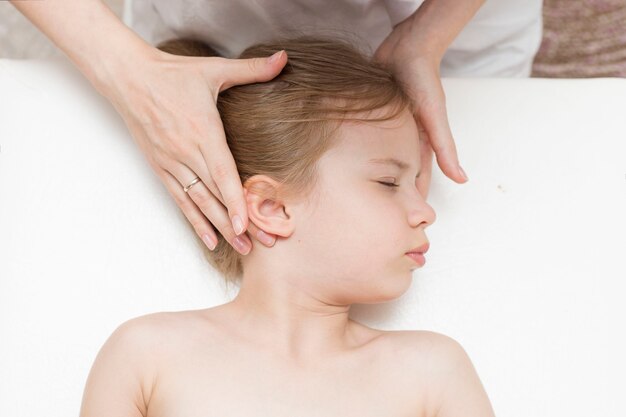 Uma menina de sete anos em uma consulta com um osteopata. osteopatia pediátrica. dores de cabeça em crianças em idade escolar. correção do crânio, coluna vertebral.