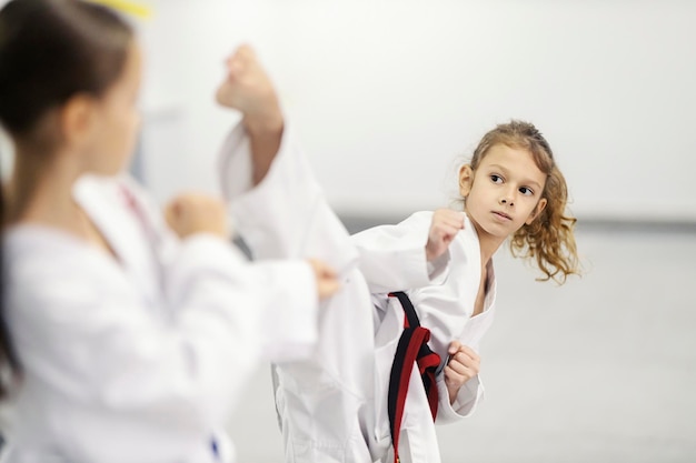 Uma menina de taekwondo está chutando durante o combate na escola de artes marciais