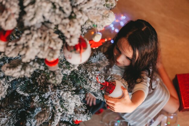 uma menina decorando uma árvore de natal em casa