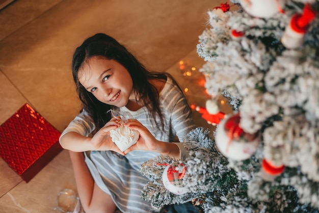 uma menina decorando uma árvore de natal em casa