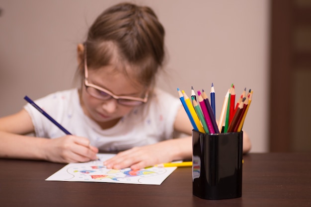 Uma menina desenha com lápis de cor